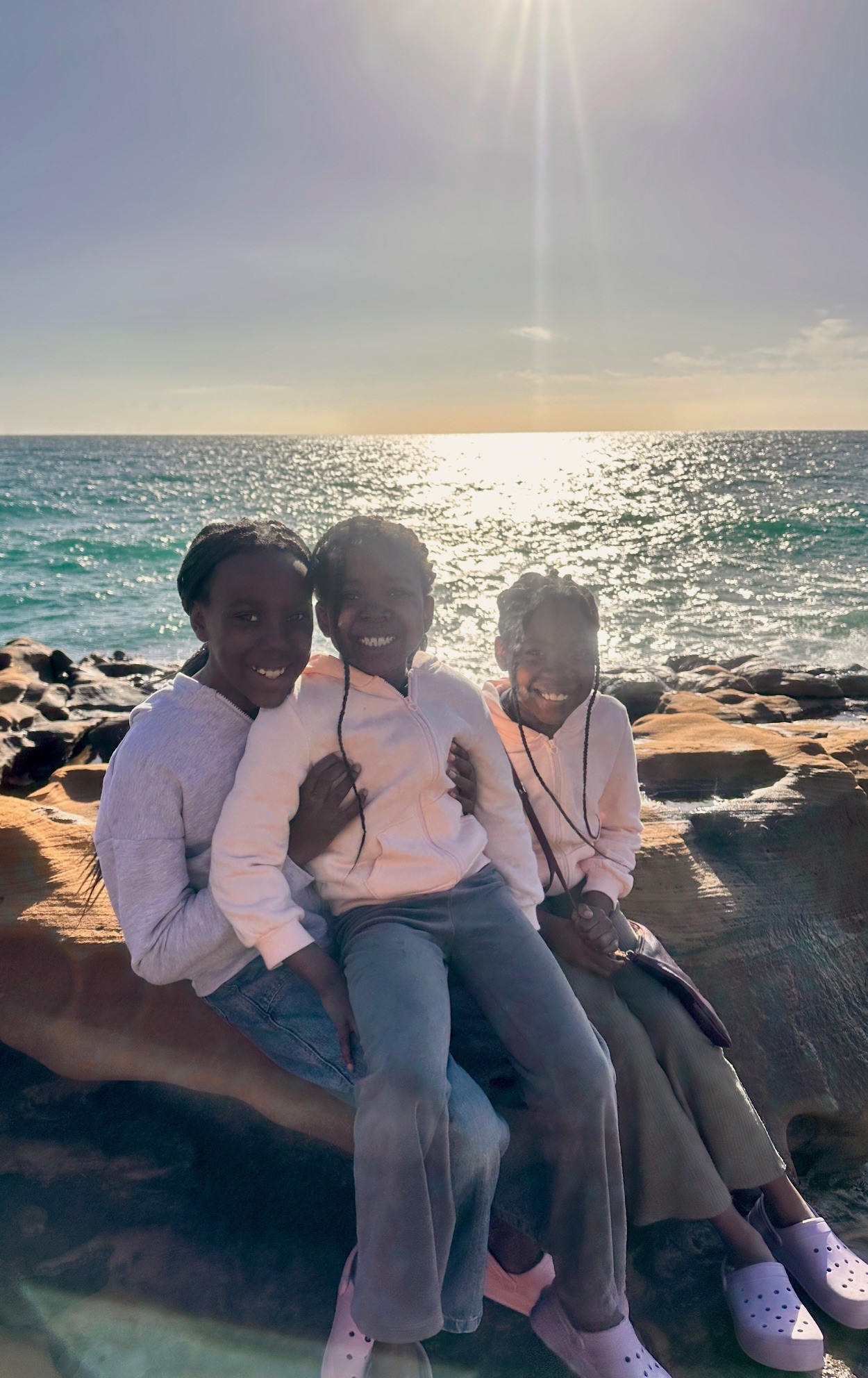 Three daughters at sunset by the ocean